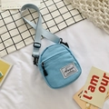 Light blue mini canvas crossbody bag with adjustable strap on white bedding - Blue
