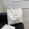 Borsa tote in velluto a coste bianco con toppa logo su un divano in pelle nera - Bianco