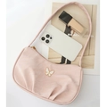 Pink pleated underarm bag with butterfly ornament placed on a fashion magazine - Pink