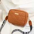 Quilted brown crossbody bag with wide patterned strap and gold hardware on silk background - Brown
