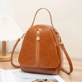 Brown waxed faux leather lady backpack with front vertical zipper on wooden table - Brown