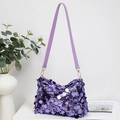 Borsa a spalla in paillettes viola con tracolla regolabile su un tavolo bianco - Viola