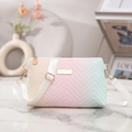 Detail of gradient crossbody bag with V-shaped quilting and gold hardware on marble surface - Gradient Pink