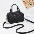 Chic black quilted tote bag with gold hardware and top handles on a stylish prop setting - Black Quilted