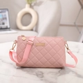 Pink quilted crossbody bag with gold hardware and adjustable strap on marble surface - Pink