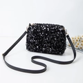 Elegante bolso bandolera de lentejuelas negras con detalles dorados sobre fondo blanco - Negro