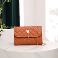 Detail der orangefarbenen gesteppten Tasche mit Perlen-Katzenquaste und Goldkette - Braun