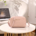 Rosafarbene Stepptasche mit Wellenstickerei und Goldlogo auf weißem Marmortisch - Rosa