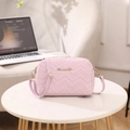 Pink quilted crossbody bag with wave embroidery and golden S logo on marble tabletop - Violet