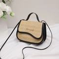 Straw handbag with black leather trim and gold logo on a white fabric background - Black