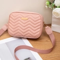 Pink quilted crossbody camera bag with wide strap and golden hardware on wood - Pink