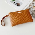 Brown wave quilted wristlet clutch with gold bar detail on textured leather surface - Tan