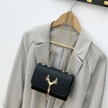 Black woven shoulder bag featuring a golden deer head clasp and metallic fringe detail - Black