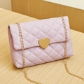 Quilted lavender handbag with golden heart clasp and chain strap on wood surface - Purple