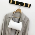Bolso de hombro acolchado blanco con detalles dorados, presentado sobre un blazer gris - Blanco