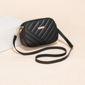 Minimalist black quilted crossbody bag with gold hardware on a modern white pedestal - Black