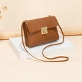 Elegante bruine gewatteerde crossbodytas met gouden draaisluiting op een wit voetstuk - Bruin