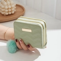Mint green mini wallet with V-stitch quilting and double gold zippers in hand - Green