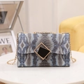 Blue gradient snakeskin printed crossbody bag with golden chain strap on a table - Blue