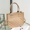 Elegant khaki quilted tote bag with dual handles and fabric shoulder strap on table - Apricot
