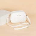 White quilted crossbody bag with dual zippers and gold logo on leather surface - White
