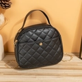 Elegant black quilted handbag with golden chain strap and top handle on a wooden surface - Black