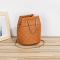 Borsa a secchiello marrone trapuntata con catena dorata su un tavolo in legno minimal - Marrone