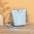 Minimalist light blue PU leather bucket bag with golden round clasp on wooden desk - Blue