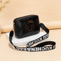 Black square shoulder bag featuring orange Halloween pumpkin face and wide letter strap - Black