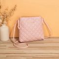 Gesteppte hellrosa Umhängetasche mit Rautenmuster und goldenem Logo auf Holzoberfläche - Rosa