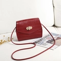 Deep red crocodile pattern small square shoulder bag with pearl lock detail on white sofa - Red