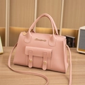 Bolso Boston rosa con asas dobles y detalles metálicos dorados en escena elegante - Rosa