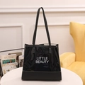 Glossy black tote bag with white Little Beauty print and long shoulder straps - Black
