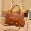 Elegante borsa a mano in pelle marrone con logo dorato e tracolla in un interno accogliente - Marrone