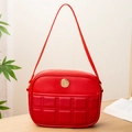 Red quilted leather shoulder bag for women with gold circular logo on wood table - Red