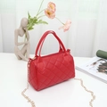 Red quilted boston handbag with dual handles and gold chain strap in a lifestyle setting - Red