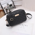 Minimalist black quilted crossbody bag with fish-scale texture and wide strap on table - Black
