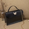 Elegant black mini square bag with butterfly clasp and gold chain strap on warm fabric - Black