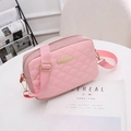 Pink quilted shoulder bag with gold hardware and adjustable strap on a white table - Pink