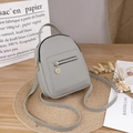 Mini zaino chic in pelle PU grigia con cerniera dorata su un tavolo in legno - Grigio