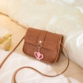 Brown rectangular crossbody bag featuring embossed cartoon patterns and a heart pendant - Brown
