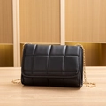 Elegant black quilted crossbody bag with golden chain strap on a wooden table - Black