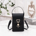 Vertical black crossbody phone bag with gold cat pendant on marble surface - Black