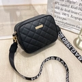 Black quilted crossbody bag with stylish wide letter strap on a wooden background - Black