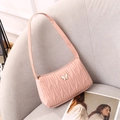 Pale pink quilted underarm bag featuring a white enamel butterfly buckle on a sofa - Pink