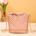 Pink drawstring bucket bag with V-shaped quilting and gold chain strap in a studio setting - Pink