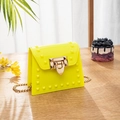 Neongelbe PVC-Gelee-Tasche mit Goldnieten und Kettenriemen auf einem Holztisch - Gelb