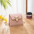 Pink jelly mini crossbody bag with gold pyramid studs and leaf lock on wooden table - Apricot