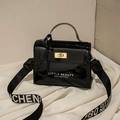 Glossy black patent leather mini handbag with gold twist lock and woven shoulder strap - Black