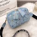Light blue geometric crossbody bag with a colorful ribbon strap on a soft white rug - Blue